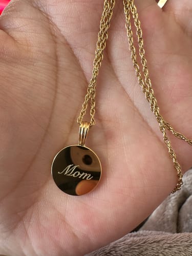 Customer holding the gold Engravable Classic Disc Necklace, with the round pendant engraved with 'Mom'.