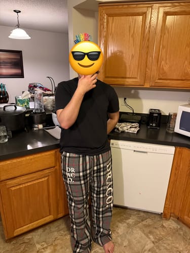 Reviewer showing off the stylish fit of the plaid Draco Pajama Pants in a kitchen.