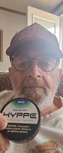 Reviewer holding a black, circular can of HYPPE Glacier Mint nicotine pouches.