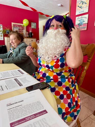 Customer in a colorful clown costume and fake beard, playing the Circus Murder Mystery game with the character guide.