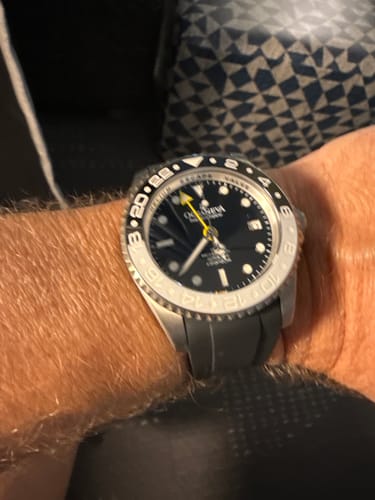 Customer wearing the Oceaneva GMT watch on their wrist, showing the white bezel and black silicone strap.