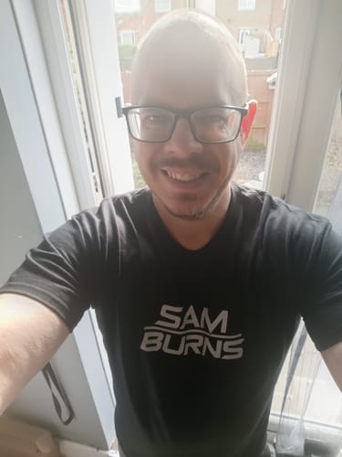 Reviewer smiling while wearing a custom black unisex t-shirt with a white graphic on the front.
