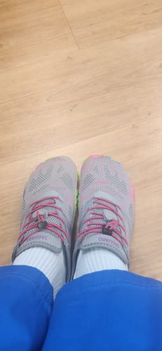 Customer's feet from a top-down view, wearing grey and pink shoes with white socks on a wood floor.