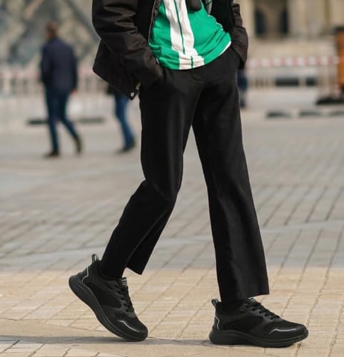 Customer walking outdoors wearing black Ortho Air shoes with black pants and a jacket.