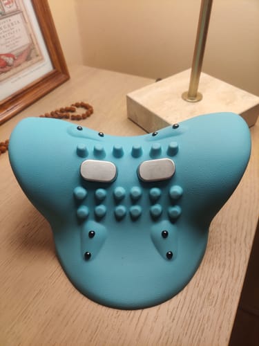 A vásárló világoskék Neckoria elektromos nyakmasszírozója egy fa asztalon.