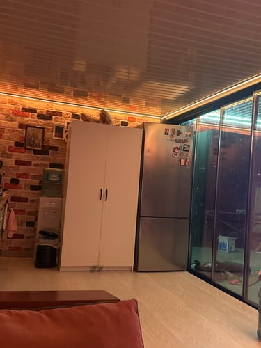Müşterinin, kapıları kapalı halde bir buzdolabının yanında duran beyaz çok amaçlı dolabı.