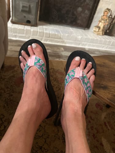 Reviewer showing the fit of their Seashell Soiree flip flops with vibrant pink and green seashell straps.