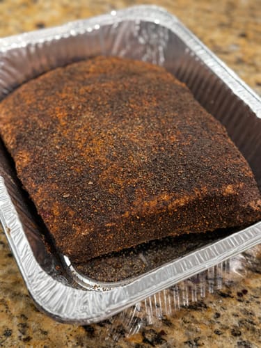 Customer's seasoned USDA Choice Bone-In Short Ribs sitting in a foil pan, ready for cooking.
