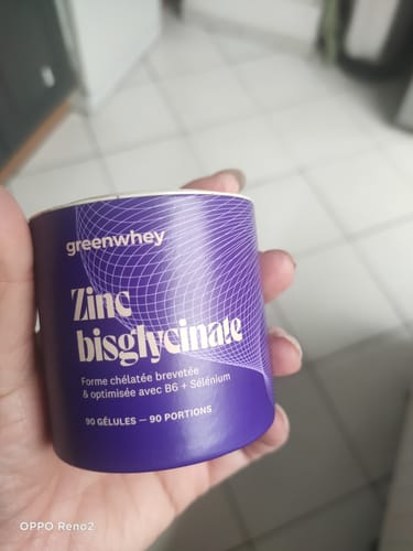 Client tenant le pot violet du complément alimentaire Zinc Bisglycinate dans sa main.