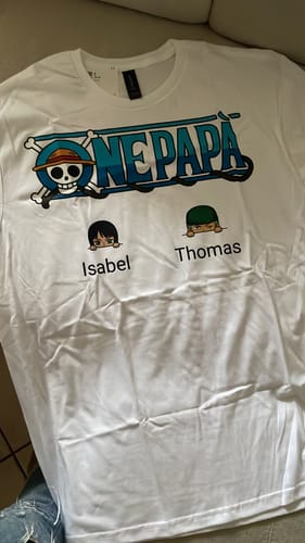 Kunde zeigt das personalisierte weiße „One PAPÀ“-T-Shirt mit zwei Figuren und den Namen Isabel und Thomas.