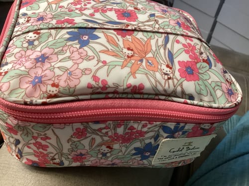 Reviewer's close-up of the Sanrio cosmetic bag showing the colorful floral pattern with hidden Hello Kitty characters.