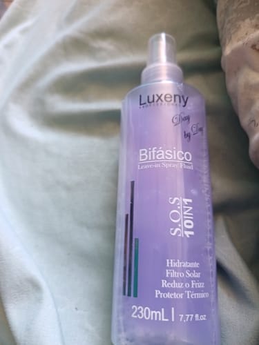Primer plano del Spray Bifásico 10 en 1 de un cliente, mostrando el producto morado dentro de la botella transparente.