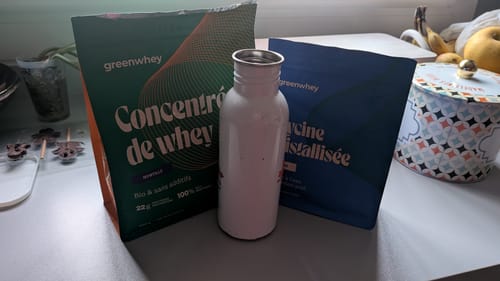 Photo d'un client montrant le sachet de Protéine de Whey Bioproduit et un shaker blanc sur un comptoir.