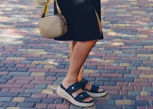 Customer wearing the dark blue Relief sandals with a white platform sole on a colorful cobblestone path.