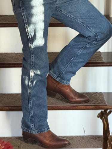 Customer wearing blue Slim Fit Jeans, showing the boot cut fit over brown boots.