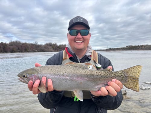 Customer holding up a large rainbow trout caught from the river.