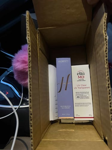 Reviewer shows the Hydrinity Restorative HA Serum inside its shipping box alongside another product.