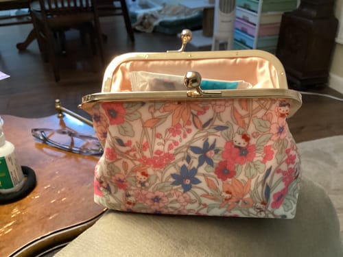 Customer's Sanrio Kiss-Lock Floral Pouch sitting open on a chair, showing the detailed pattern and pink interior.