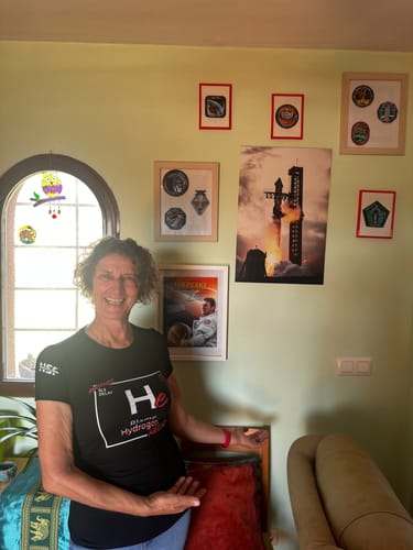 Reviewer smiling while wearing the black 'Blame Helium' t-shirt in a room decorated with space-themed posters.