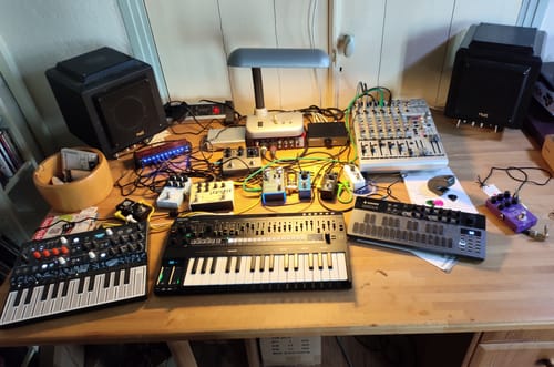 Rezensent zeigt den Donner Essential L1 Synthesizer auf einem Tisch zusammen mit anderem Musikequipment.