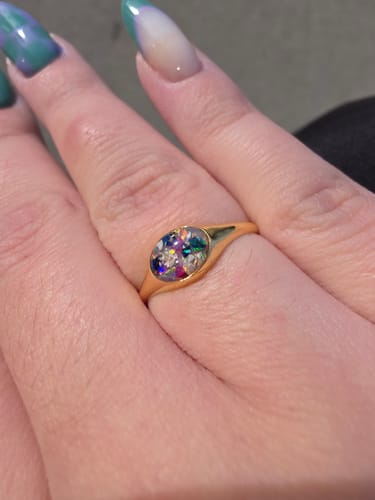 Reviewer wearing the Golden Oval Ring on their finger, showing its colorful crushed opal and ash inlay.