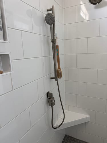 Customer's Gillian Filtered Shower Head with handheld wand installed in a white tiled shower.