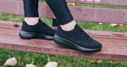 Customer wearing black Air Glide shoes while sitting on a park bench.