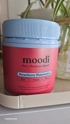 Customer's tub of Strawberry Watermelon Pre + Probiotic Blend with its red label and blue lid, sitting on a shelf.