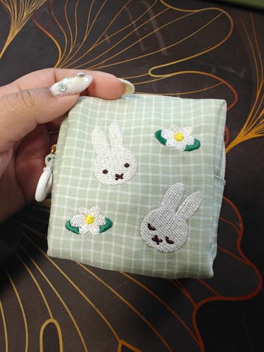 Reviewer's hand holding the green gingham Miffy Mini Pouch, showing the embroidered design.