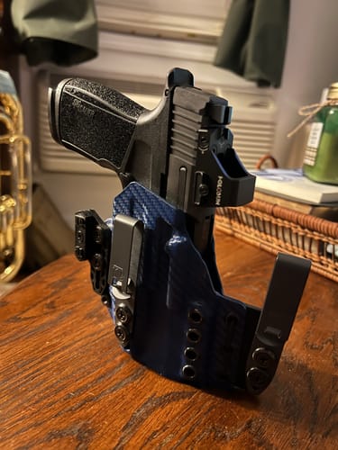 Customer's blue XIPHOS ELITE holster, shown holding a handgun equipped with a light and optic.