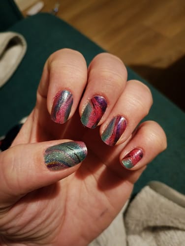 Reviewer's hand showing their nails with the applied Cosmos nail gels, featuring a shimmery multi-colored design.