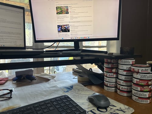 Customer's tall stacks of Chewy Watermelon tins sitting on a desk next to their computer.
