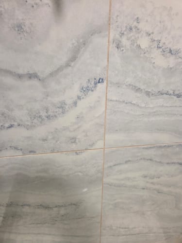Customer's close-up of tile with orange, discolored grout before cleaning.