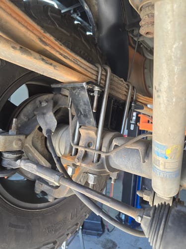 Close-up of a customer's black lift block and U-bolts installed on a truck's rear leaf spring suspension.
