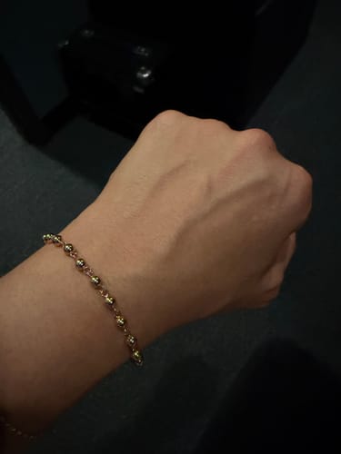 Customer's wrist wearing the polished gold Bauble Bracelet.