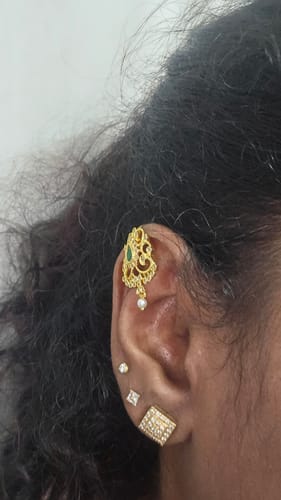 Customer wearing the gold Tarika Amara Earcuff with a leafy design and a small pearl drop on their ear.
