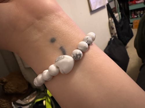 Close-up of a reviewer's wrist wearing a marbled crystal bracelet with a heart-shaped bead.