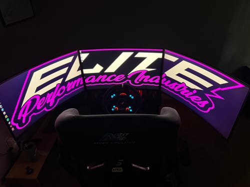 Customer's racing simulator setup showing three monitors mounted with the PRIME Triple Upgrade Kit.