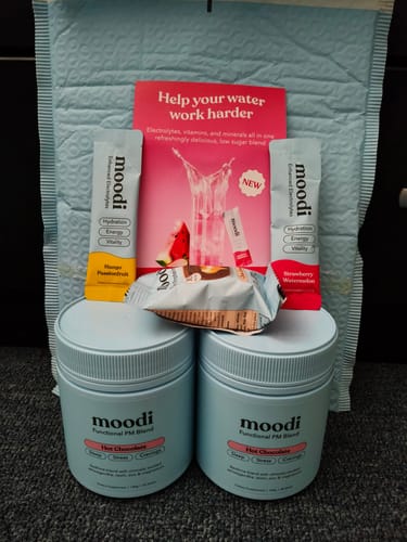 Customer's two tubs of PM Blend Hot Chocolate displayed with two sample electrolyte sachets.