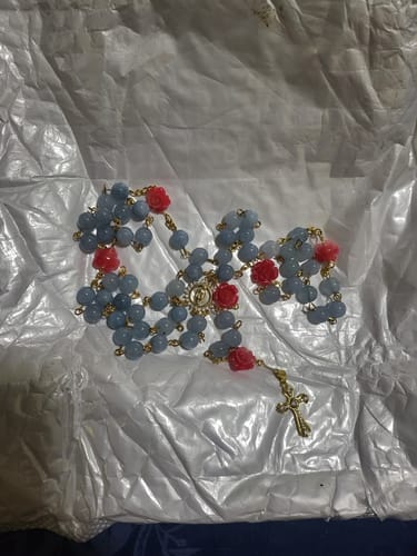 Reviewer's blue chalcedony rosary with red roses and a gold crucifix displayed on its packaging.