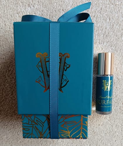 Customer's travel-size Surfari perfume beside its elegant, ribbon-tied teal gift box.