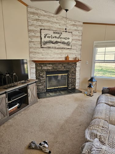 Customer's Custom Farmhouse Sign displayed as a lovely focal point above a stone fireplace in their living room.