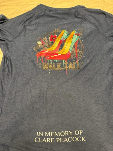 Customer's blue technical t-shirt showing the back with a colorful graphic of high heels and printed memorial text.