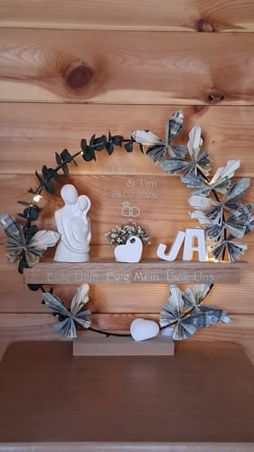 Kunde zeigt ein Hochzeitsgeschenk, bei dem ein gravierter Easy-Stick als Regal für Figuren und Blumen dient.