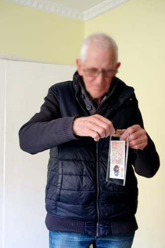 A reviewer holds The Lucky Key's clear container with a banknote inside, about to try a key in the padlock.