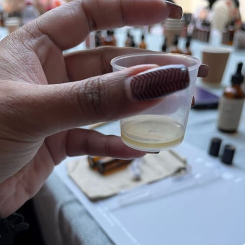 Reviewer holding a small cup with their custom perfume blend from the Perfume Making Workshop.