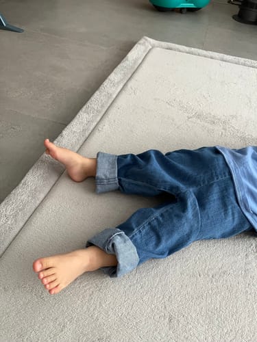 Customer's close-up of a person's bare feet resting on the soft grey Momomi® Mat on a tiled floor.