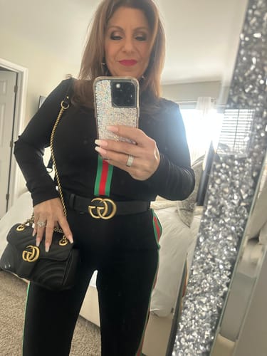 Customer in a mirror selfie, wearing a black long-sleeved top and pants with a green and red stripe.