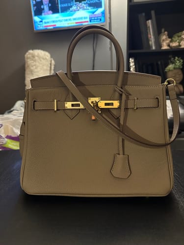 Customer's structured taupe LALUVA Warkin Bag with gold hardware sitting on a dark tabletop.
