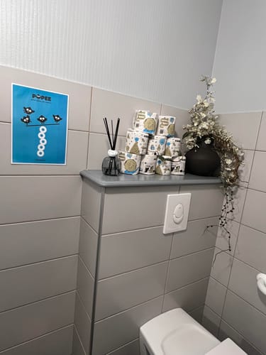 Avis d'un client : plusieurs rouleaux de papier toilette Popee empilés sur une étagère dans des toilettes.